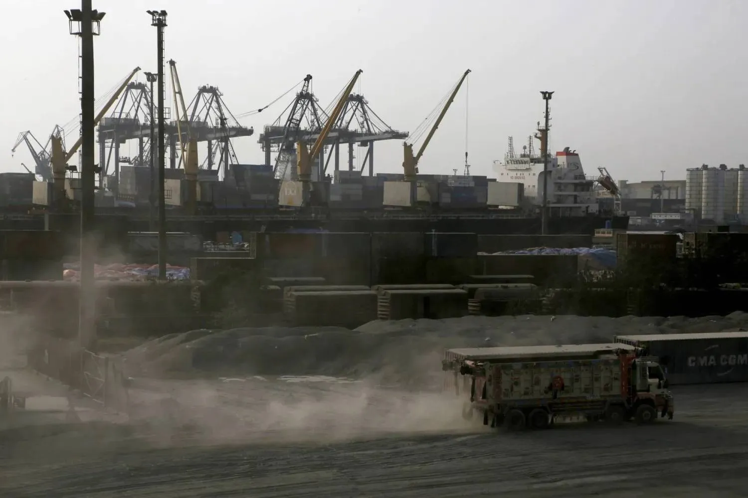 شاحنة تمر أمام رافعات في ميناء كراتشي (رويترز)