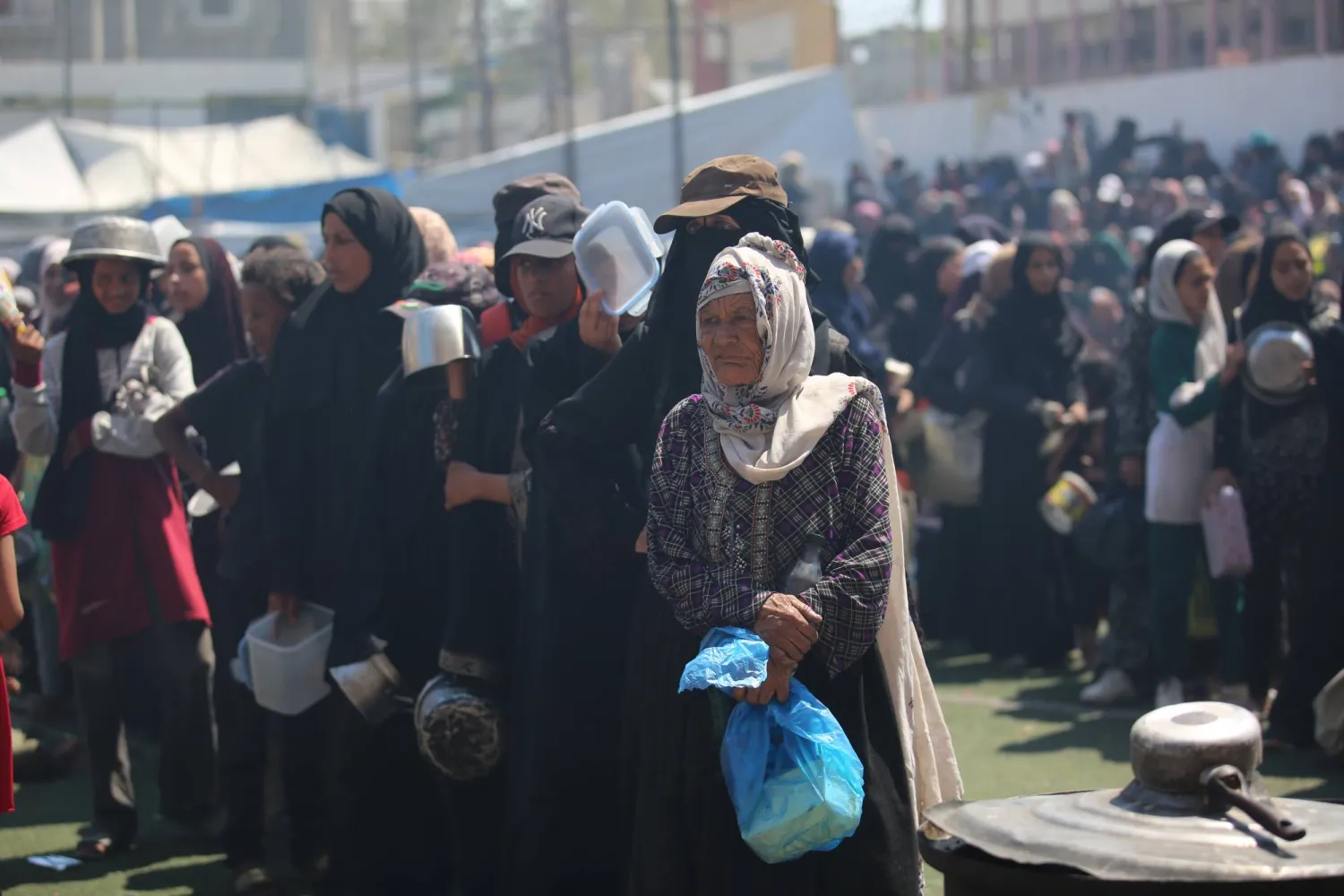 يتجمع النازحون الفلسطينيون في مطبخ خيري لتلقي حصص غذائية محدودة في ظل نقص الغذاء في مخيم النصيرات للاجئين الفلسطينيين (د.ب.أ)