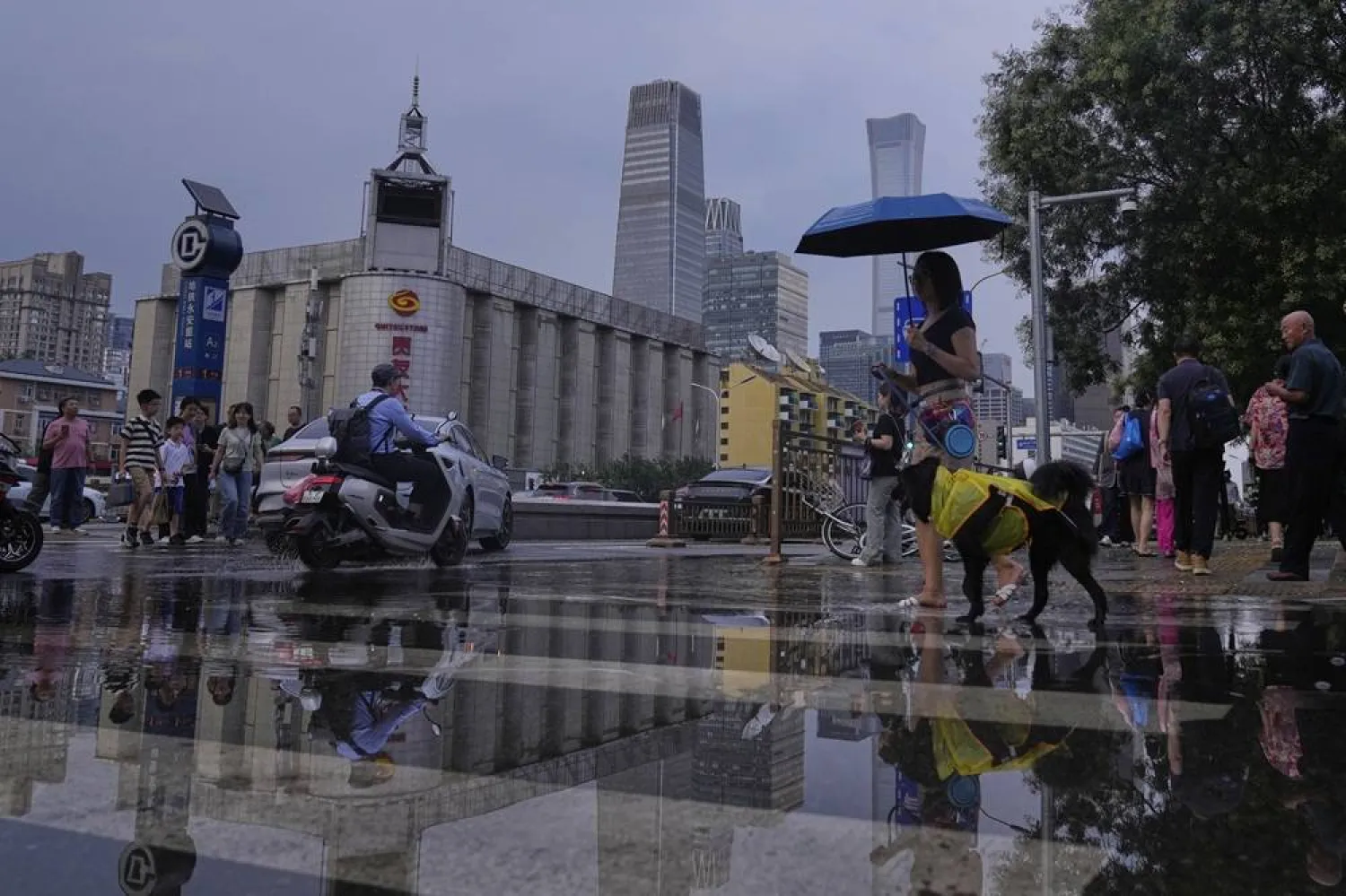  Pedestrians are reflected in rainwater as they cross the street after the downpour subside in Beijing, China, Friday, July 25, 2025. (AP) 