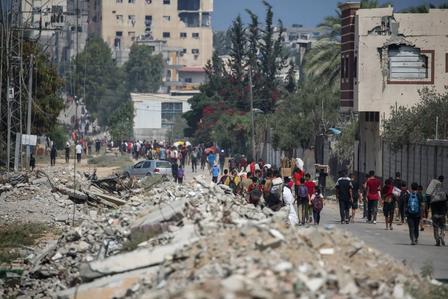 فلسطينيون نازحون في مخيم النصيرات للاجئين يحملون طرودًا غذائية ومواد أخرى تمكنوا من الحصول عليها من نقطة توزيع مساعدات من مؤسسة غزة الإنسانية في وسط قطاع غزة (أ.ف.ب)