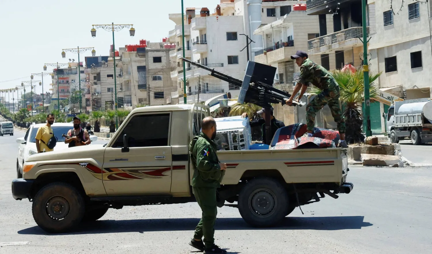  شخص يرتدي ملابس عسكرية يقف في الجزء الخلفي من مركبة في أعقاب اشتباكات دامية بين مقاتلين دروز وقبائل بدوية في مدينة السويداء بجنوب سوريا (رويترز)