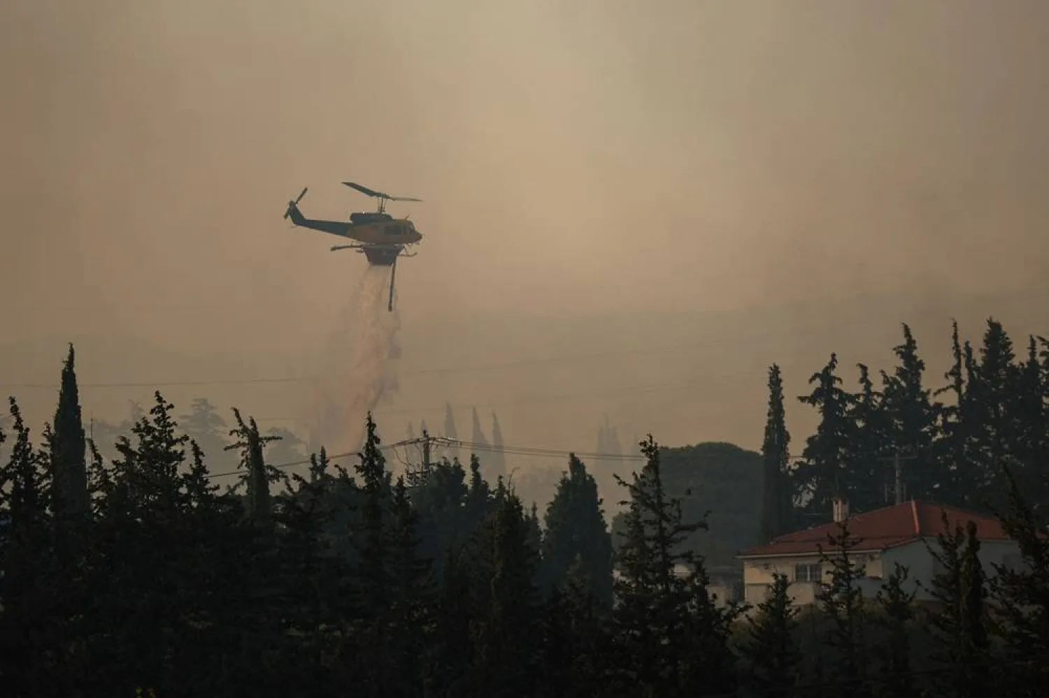 A firefighting helicopter makes a water drop as a wildfire burns in the village of Drosopigi, near Athens, Greece, July 26, 2025. (Reuters) 