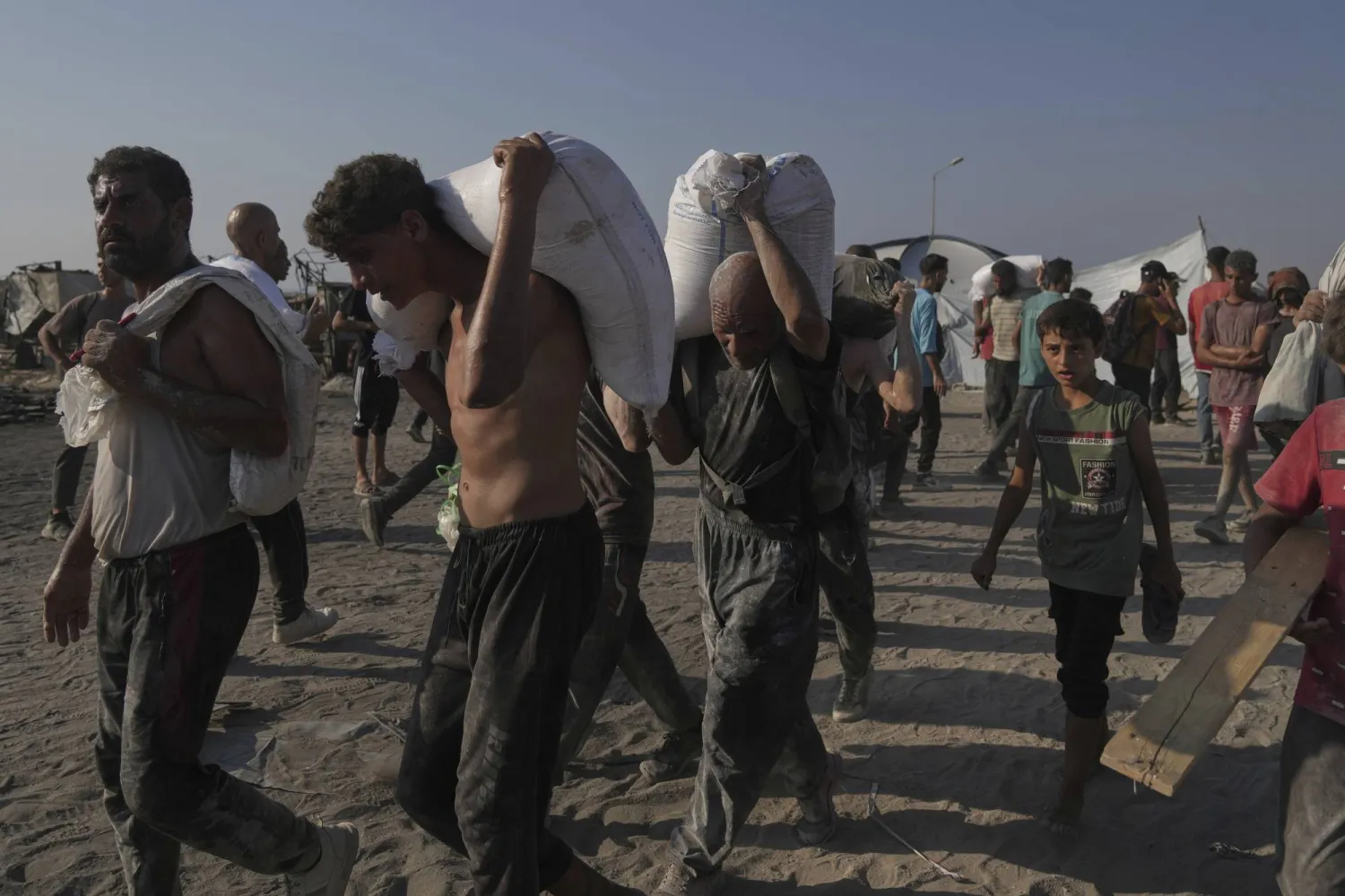Palestinians carry sacks of flour unloaded from a humanitarian aid convoy that reached Gaza City from the northern Gaza Strip, Saturday, July 26, 2025. (AP Photo/Jehad Alshrafi)