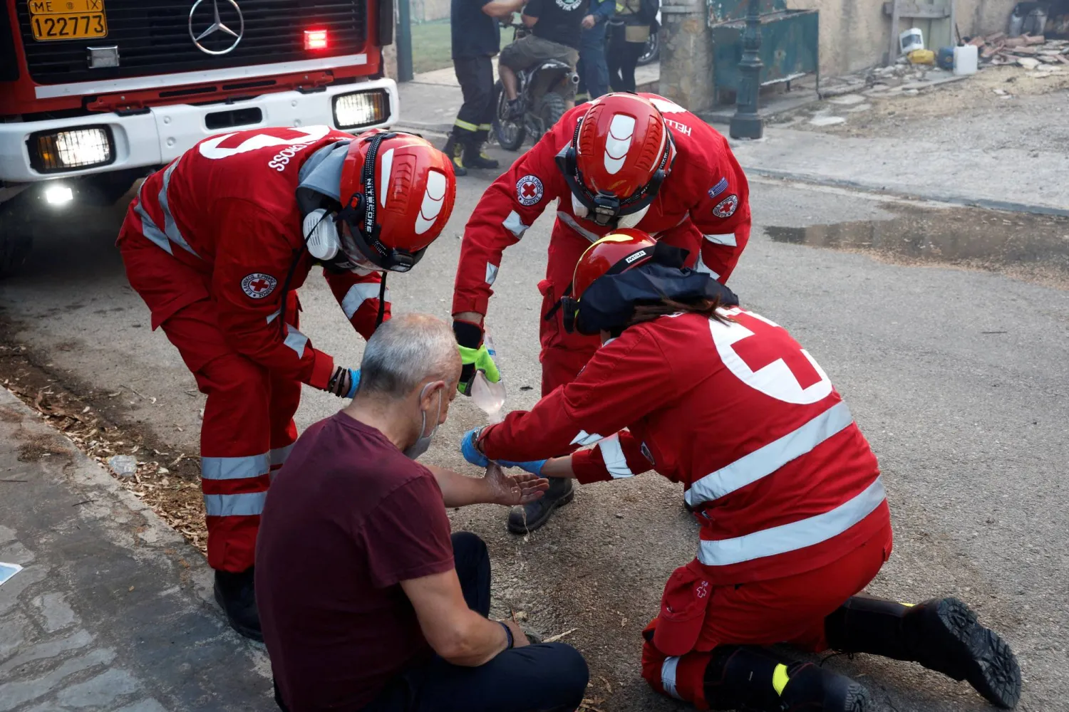 متطوعو الصليب الأحمر يساعدون شخصاً أثناء اندلاع حريق هائل في قرية كريونيري بالقرب من أثينا - اليونان 26 يوليو 2025 (رويترز)