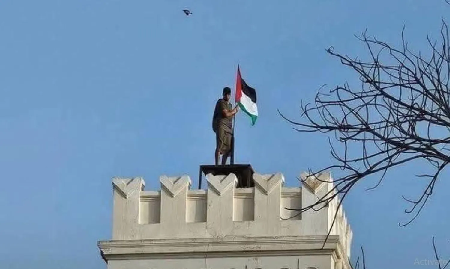 ليبي يعتلي مبنى كانت السفارة المصرية تشغله في طرابلس ويرفع عليه العلم الفلسطيني (تلفزيون «المسار»)