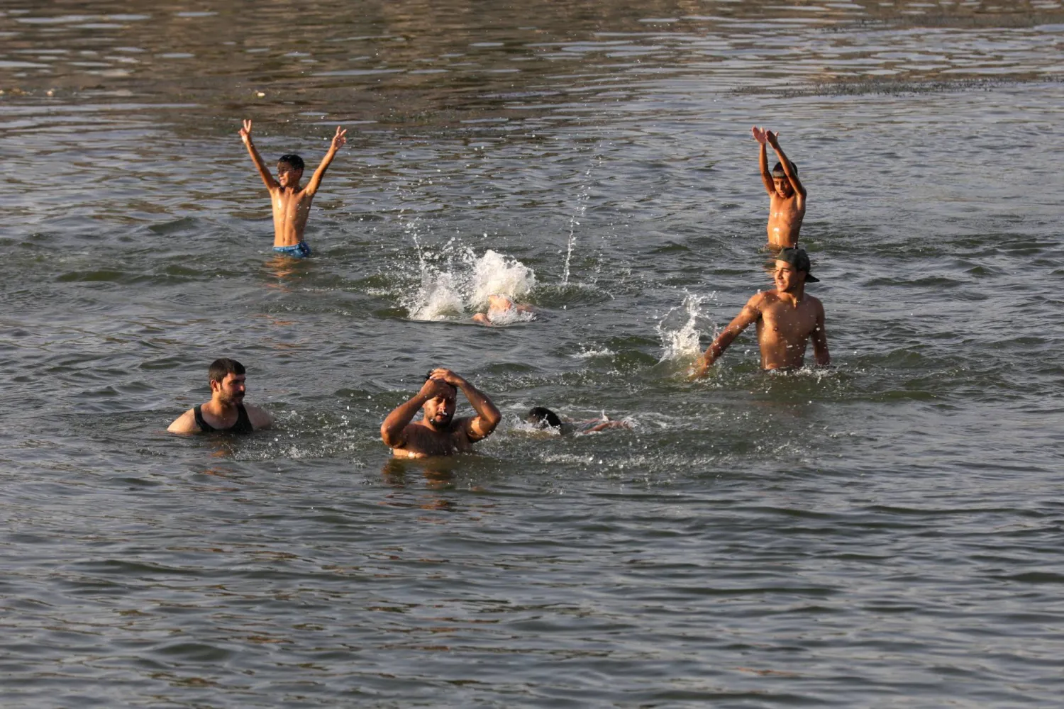 عراقيون يلجأون إلى المياه في نهر الحلة المتفرع من نهر الفرات هرباً من درجات الحرارة المرتفعة (أ.ف.ب)