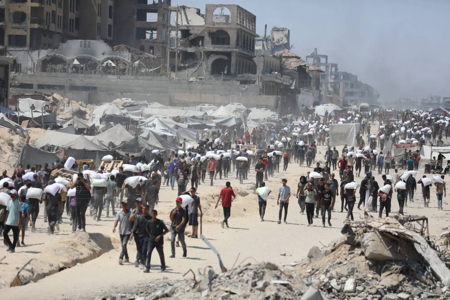 فلسطينيون يحملون أكياس المساعدات الإنسانية في قطاع غزة (د.ب.أ)