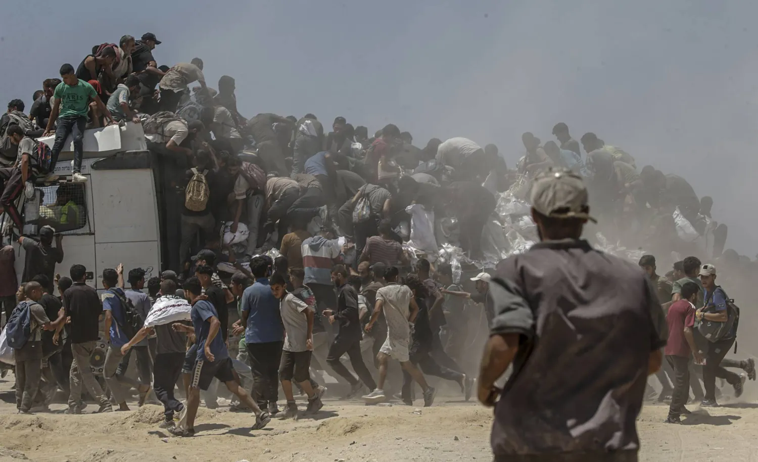 فلسطينيون يتزاحمون للحصول على أكياس دقيق من شاحنة إغاثة قرب نقطة توزيع في زكيم شمال قطاع غزة أمس (إ.ب.أ)