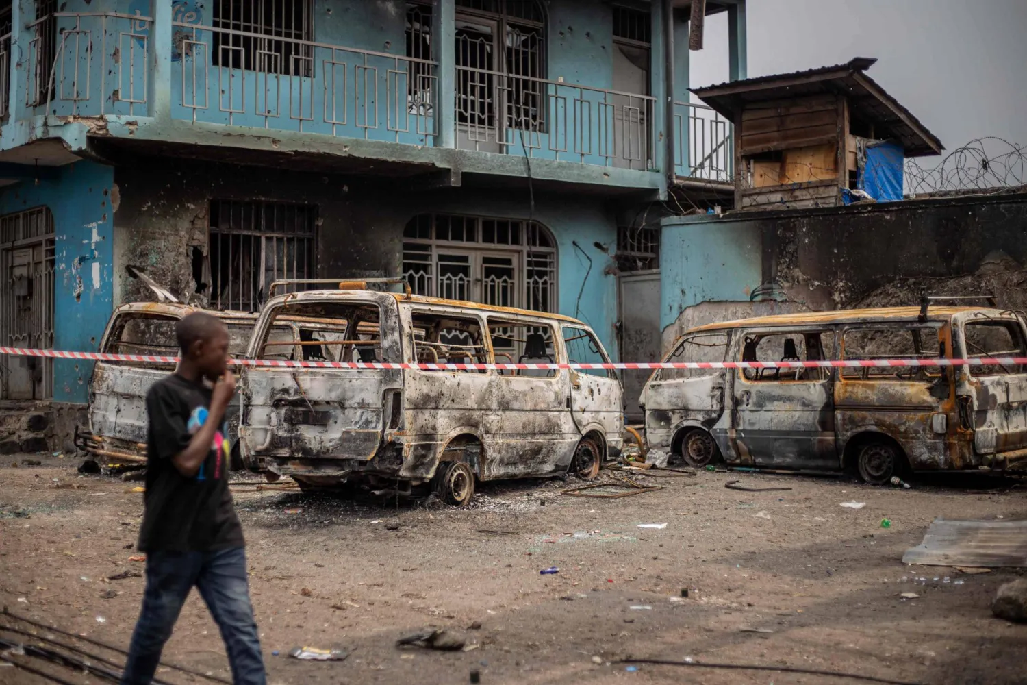 A boy walks past the wreckage of burned vehicles following clashes in Goma on January 30, 2025. (Photo by Jospin Mwisha / AFP)