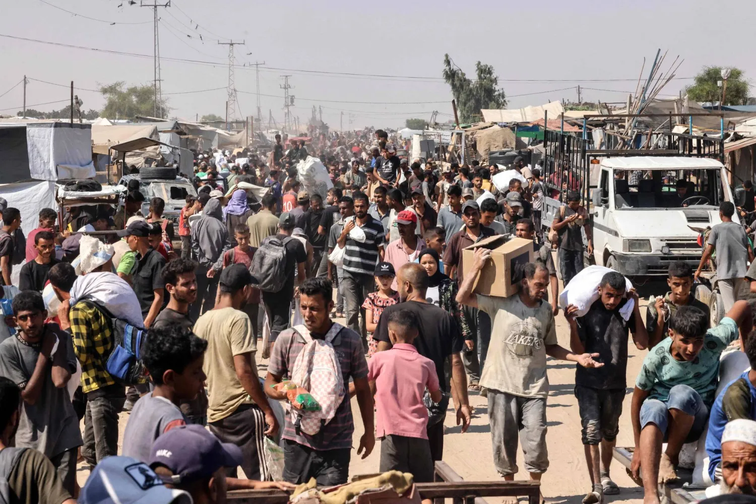 فلسطينيون يحملون طروداً غذائية بمخيم المواصي في رفح جنوب قطاع غزة (أ.ف.ب)