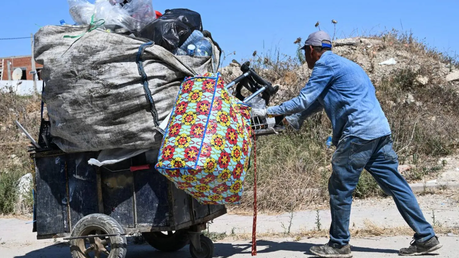 It's common to see people in Tunis weighed down by bags of plastic bottles along the roadside. FETHI BELAID / AFP
