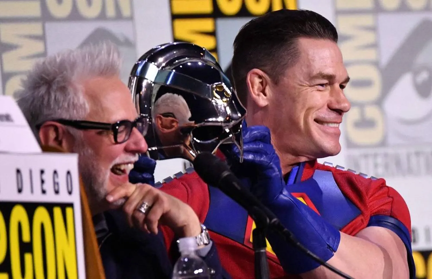 US actor John Cena (R) holds his helmet next to US director James Gunn during the "Peacemaker", Season 2, panel in Hall H of the convention center during Comic-Con International in San Diego, California, on July 26, 2025. (AFP)