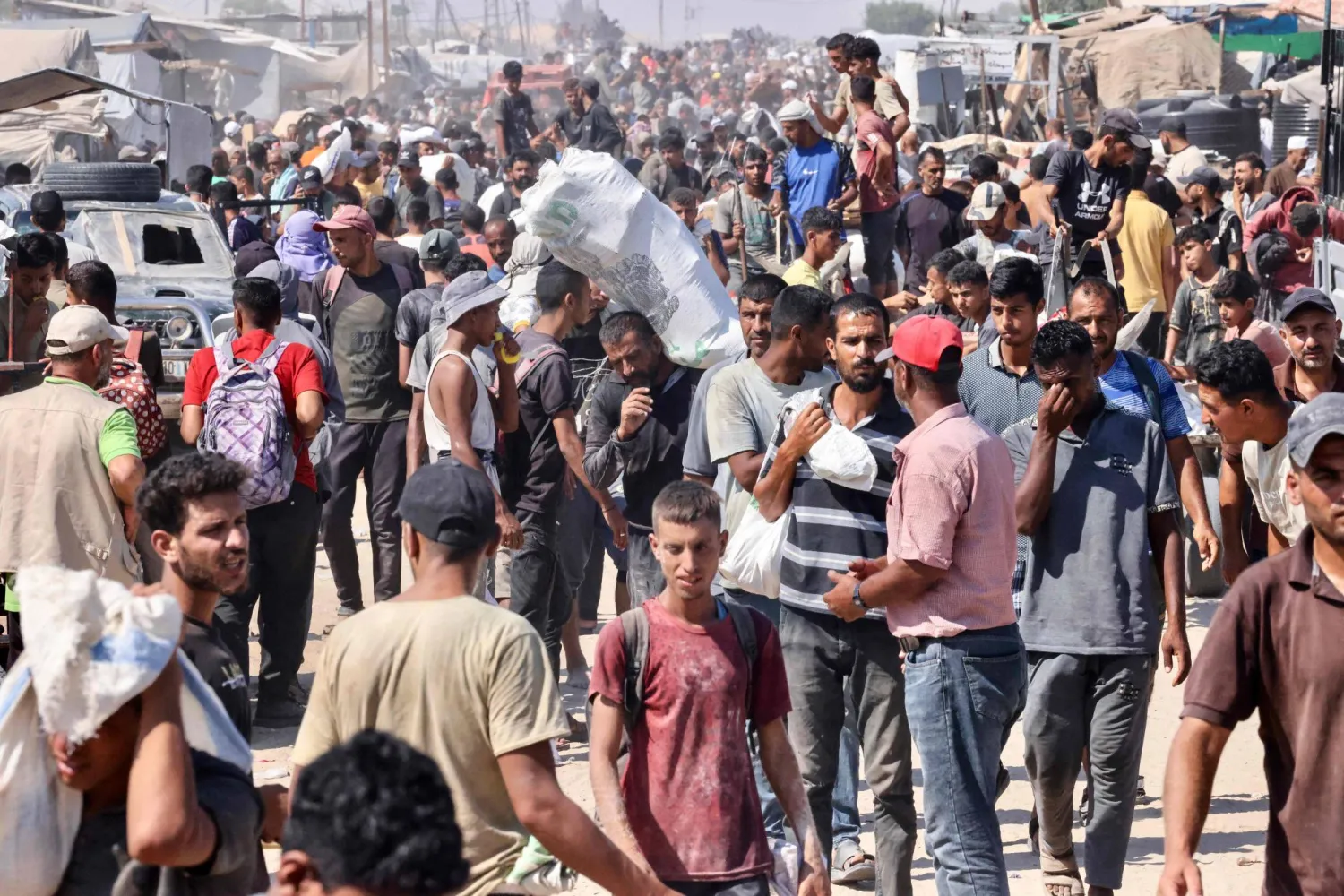 يحمل فلسطينيون طروداً وأكياساً غذائية في مخيم المواصي برفح جنوب قطاع غزة (أ.ف.ب)