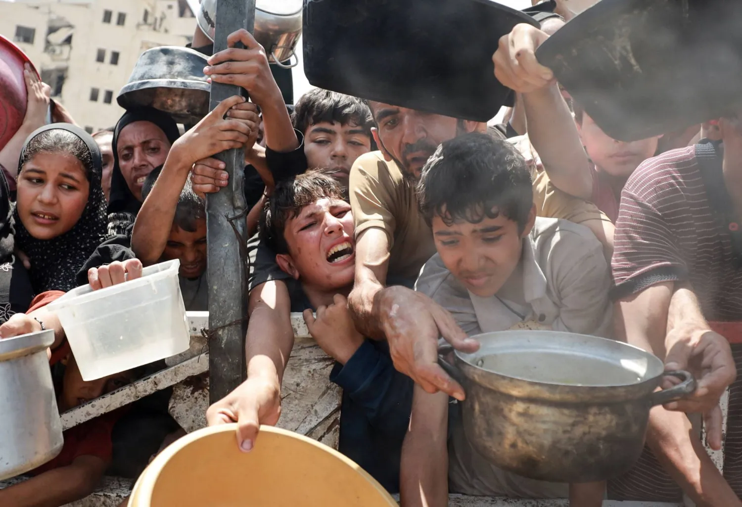 أطفال فلسطينيون يكافحون من أجل الحصول على الطعام في إحدى التكيات بمدينة غزة (رويترز)