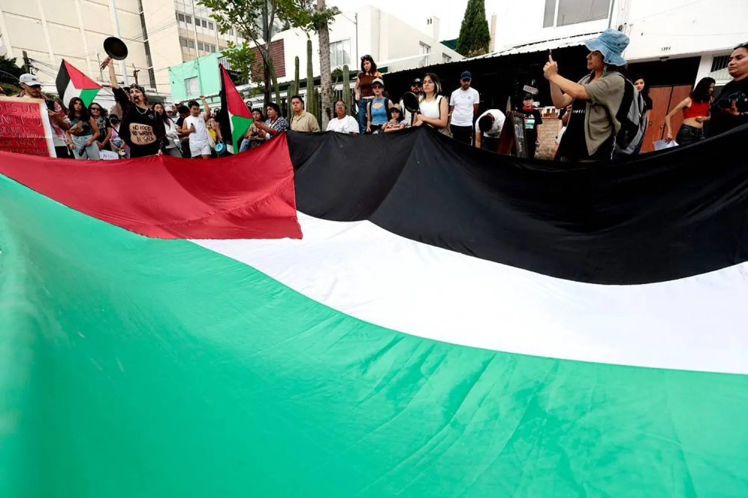 People hold a large Palestinian flag as they take part in the protest “Global Pot-Banging for Gaza” in Guadalajara, Jalisco state, Mexico on July 27, 2025. (AFP) 