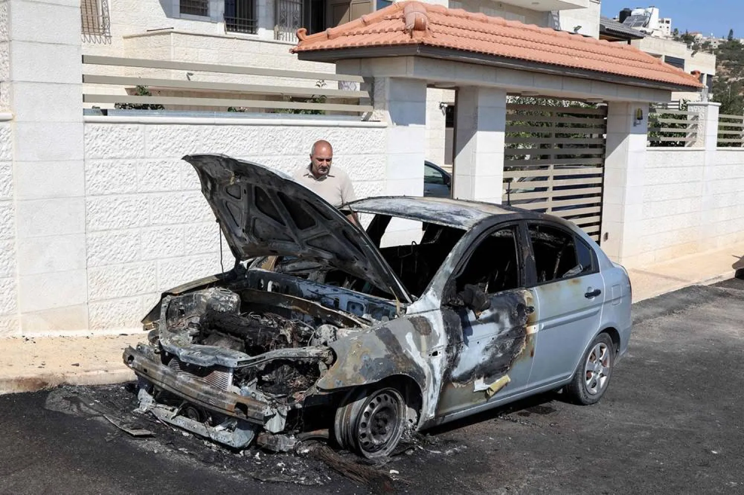  A man inspects a vehicle that was reportedly torched by Israeli settlers during an overnight attack on the Palestinian Christian village of Taybeh, northeast of Ramallah in the occupied West Bank, on July 28, 2025. (AFP) 
