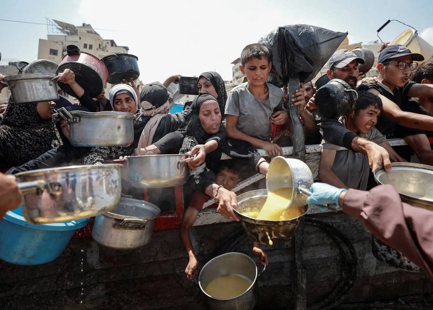 Palestinians gather to receive food from a charity kitchen, amid a hunger crisis, in Gaza City, July 28, 2025. (Reuters)