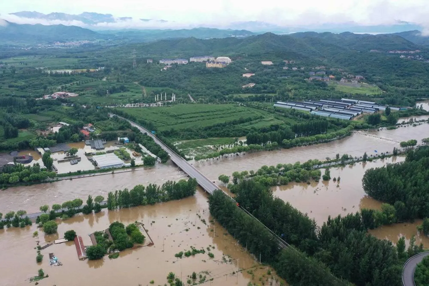An aerial view shows an overflowing river amid flooding due to heavy rains at Xinanjuang village in Miyun district, on the outskirts of Beijing on July 29, 2025. (AFP)