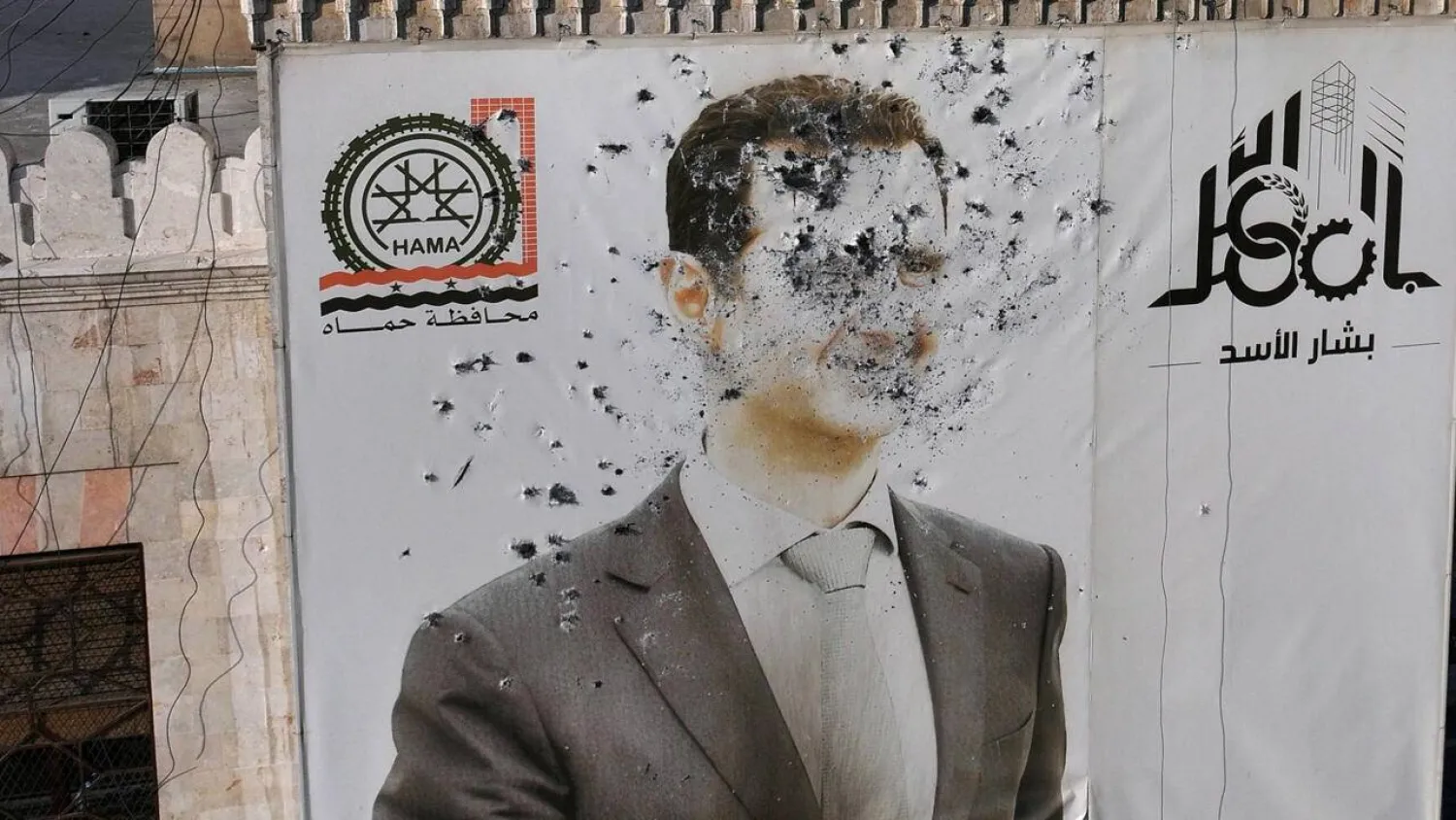 A bullet-riddled portrait of Syria's Bashar al-Assad adorns Hama's municipality following the city's capture by opposition forces on December 6, 2024. (AFP)