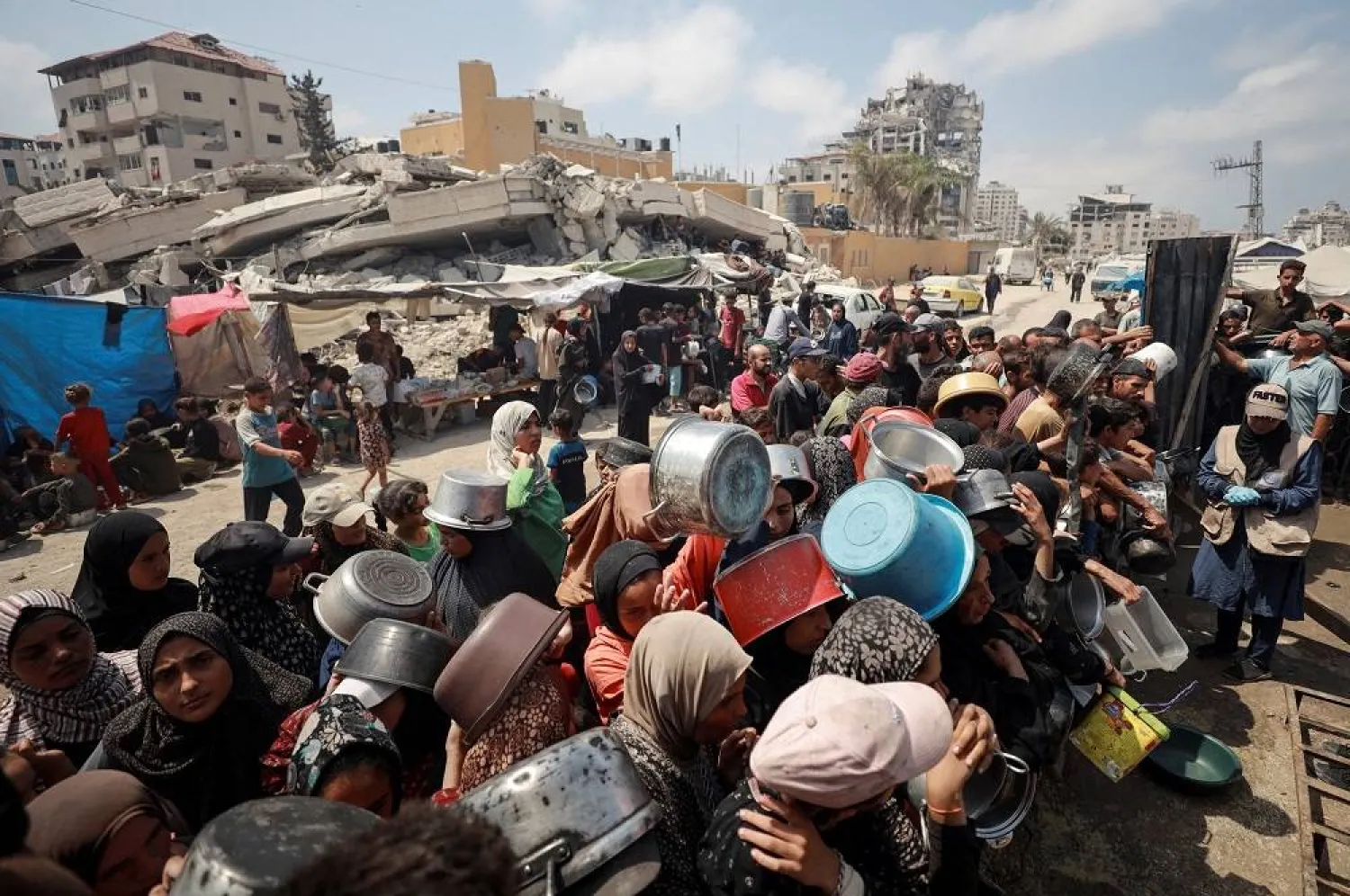 Palestinians wait to receive food from a charity kitchen, amid a hunger crisis, in Gaza City, July 28, 2025. (Reuters)