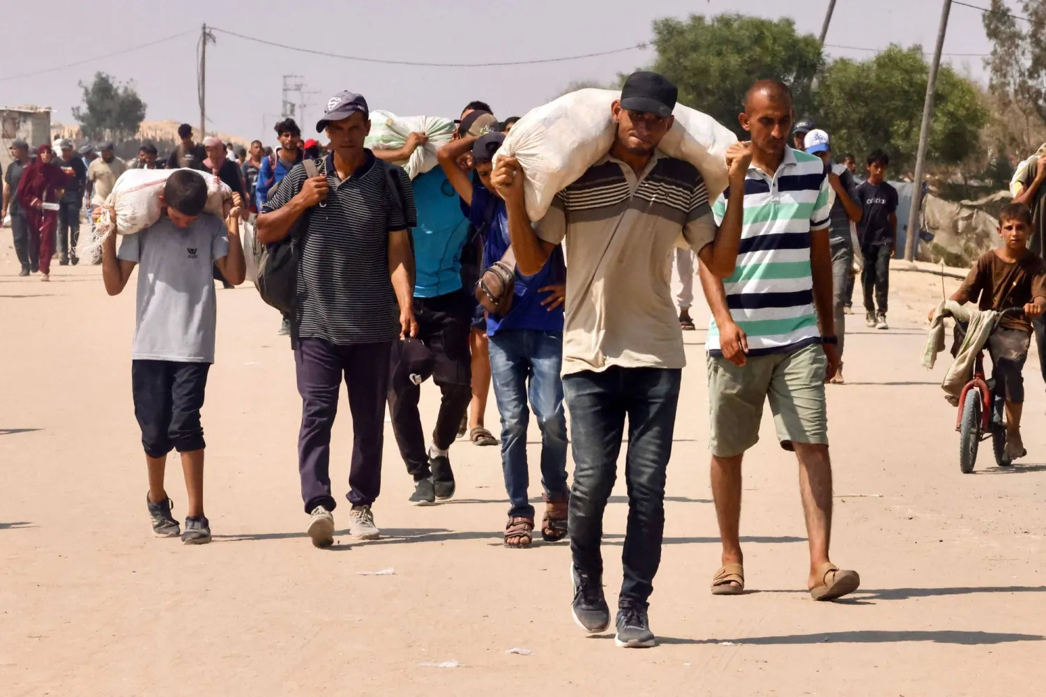 فلسطينيون يحملون مساعدات بمنطقة المواصي في رفح جنوب قطاع غزة (أ.ف.ب)