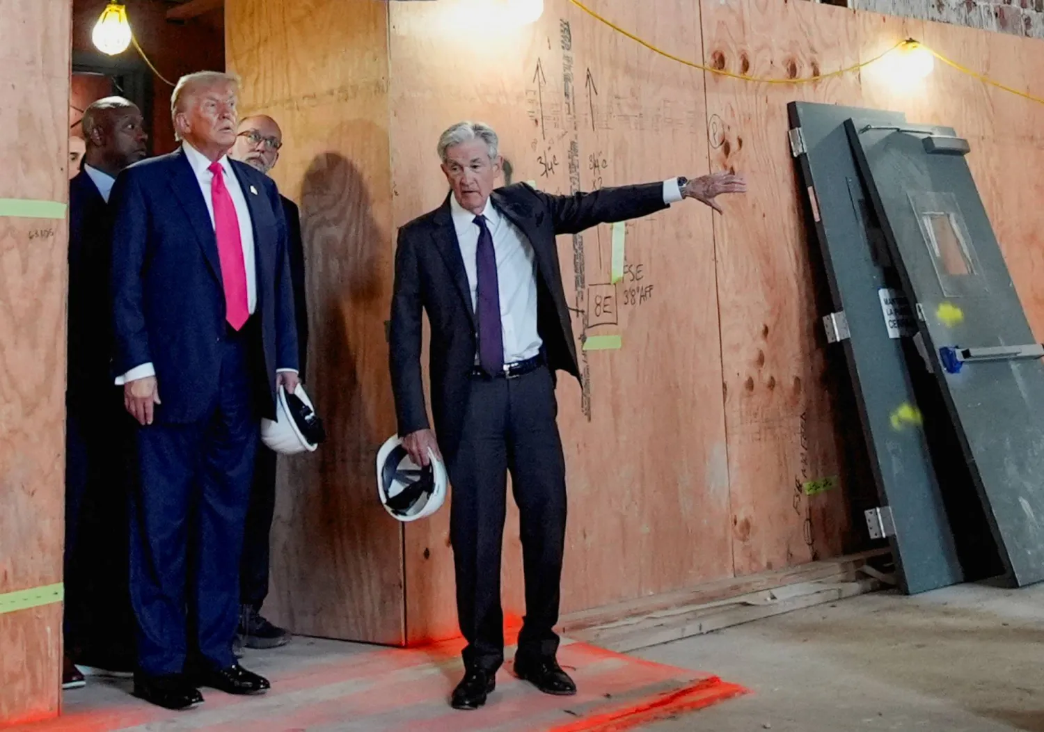 رئيس الاحتياطي الفيدرالي جيروم باول يلوّح بيده بينما ينظر إليه الرئيس الأميركي دونالد ترمب خلال جولة في مبنى الاحتياطي الفيدرالي (رويترز)