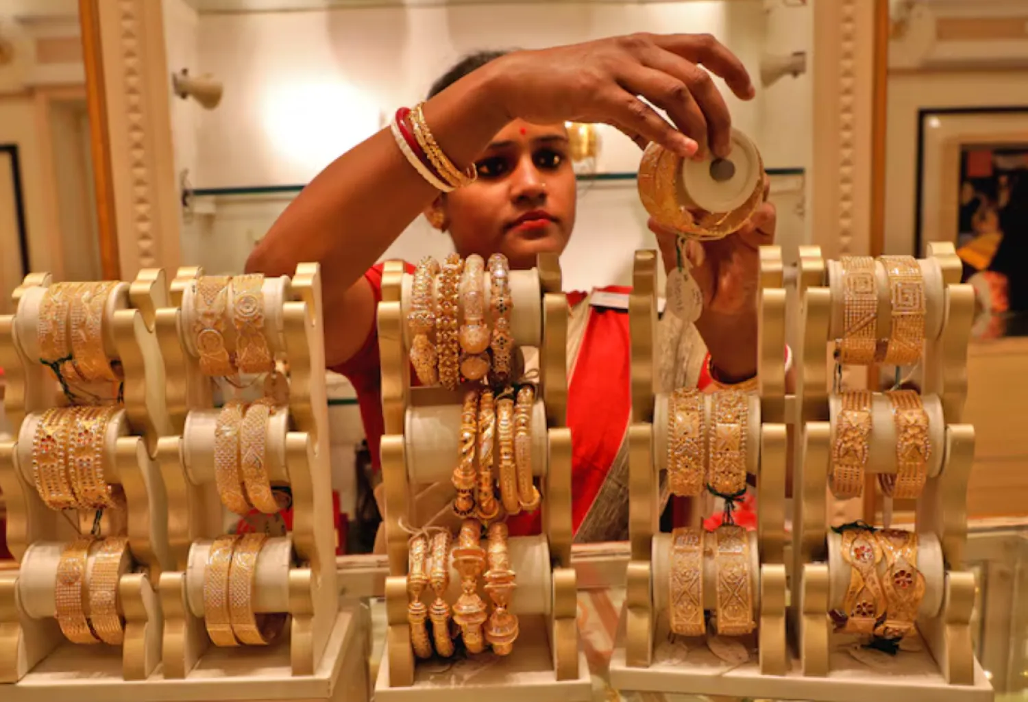 A saleswoman shows gold bangles to a customer at a jewellery showroom on the occasion of Akshaya Tritiya, a major gold buying festival, in Kolkata, India, May 3, 2022. REUTERS/Rupak De Chowdhuri/File Photo 