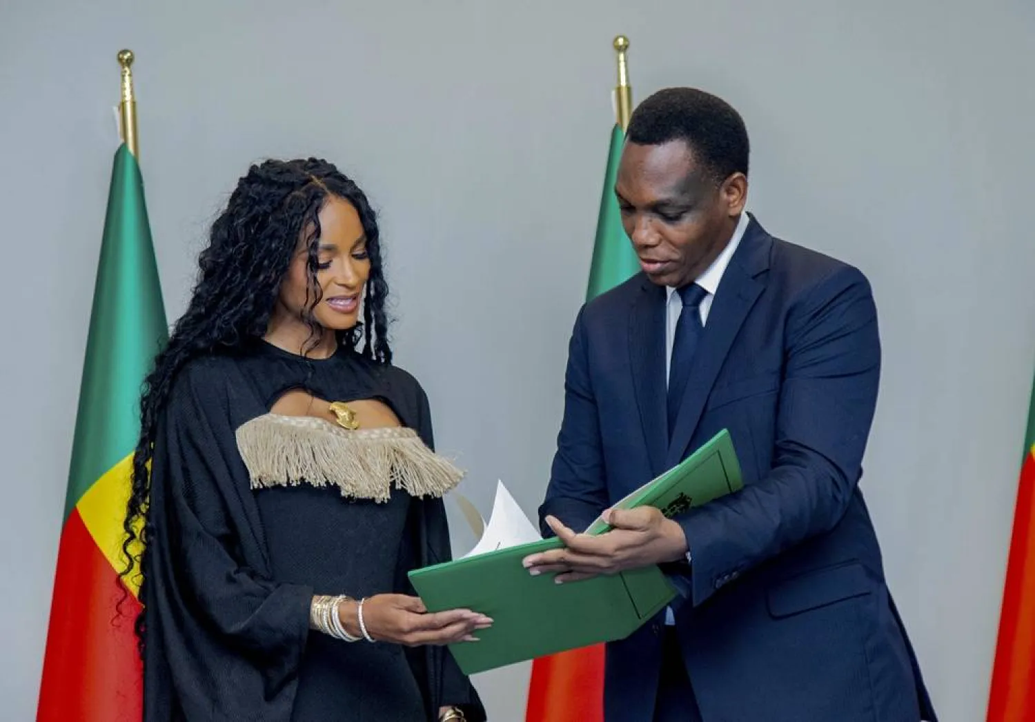  Yvon Detchenou, Benin's Minister of Justice and Legislation, right, presents citizenship documents to singer Ciara at a ceremony in Cotonou, Benin, Saturday July 26, 2025. (Benin Presidency via AP) 