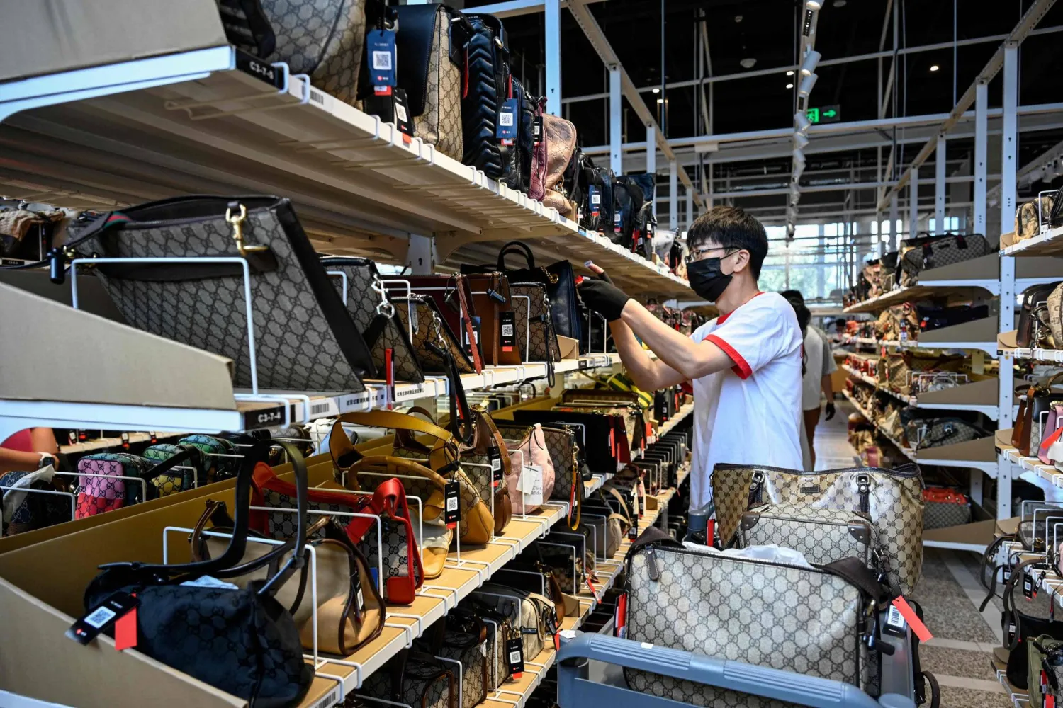 عامل في أحد متاجر الحقائب الفاخرة في المنطقة التجارية وسط العاصمة الصينية بكين (أ.ف.ب)
