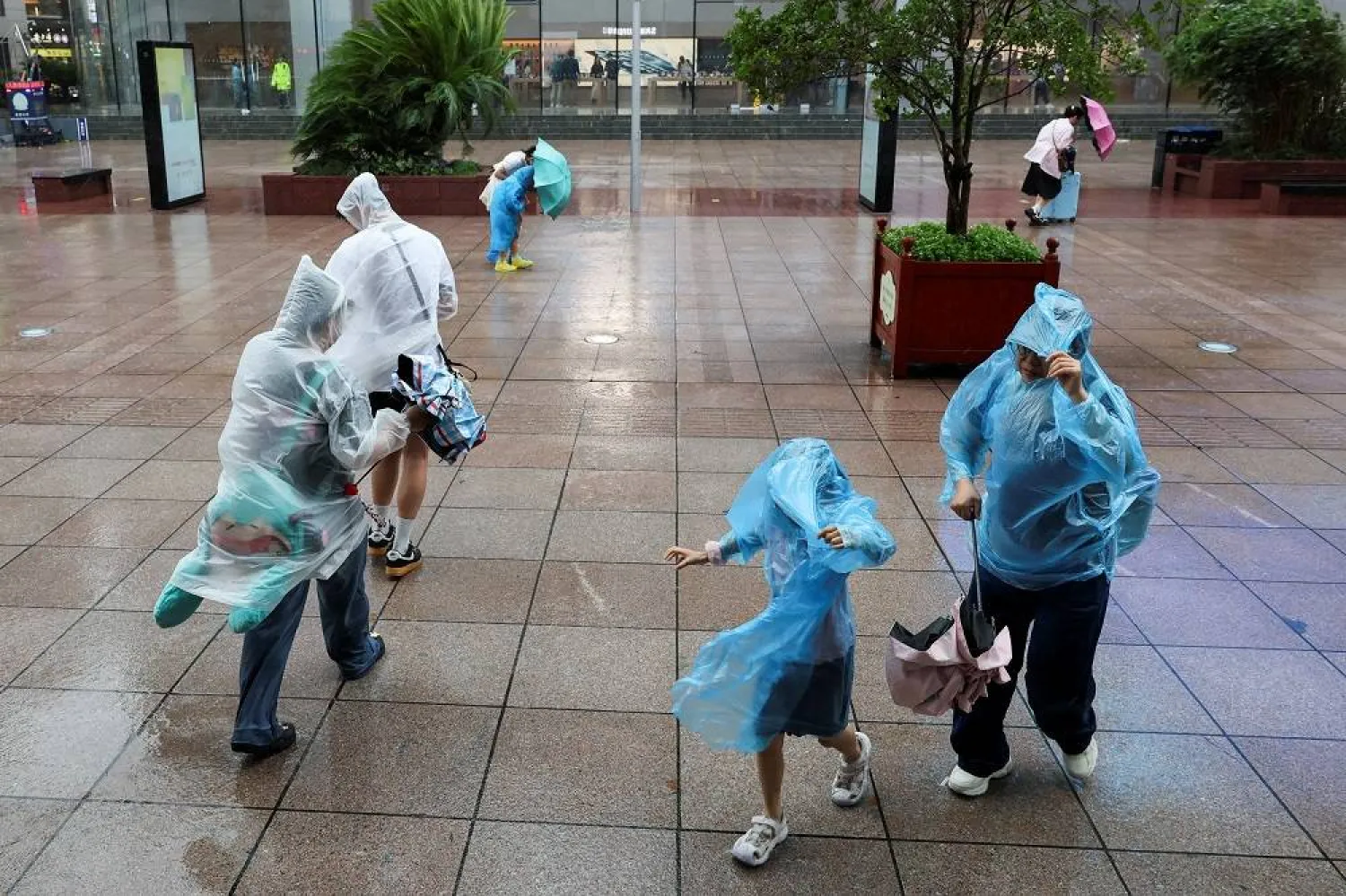 People use umbrellas and raincoats to shield themselves from heavy rain and high winds, after Tropical Storm Co-May made landfall in a nearby city, in Shanghai, China July 30, 2025. (Reuters)