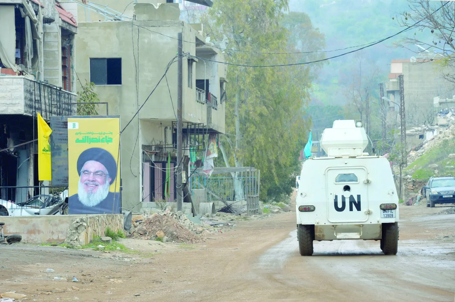 آلية تابعة لقوات «يونيفيل» في بلدة حولا بجنوب لبنان حيث تظهر صورة كبيرة للأمين العام الأسبق لـ«حزب الله» حسن نصر الله على أحد المباني (إ.ب.أ)