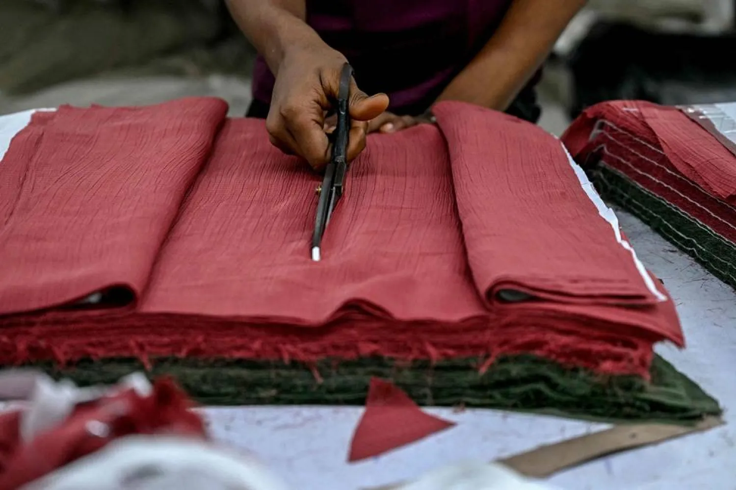 An employee cuts clothing material for dresses at the apparel manufacturing unit at Bhiwandi in the Thane district of India's Maharashtra state on July 30, 2025. (AFP)