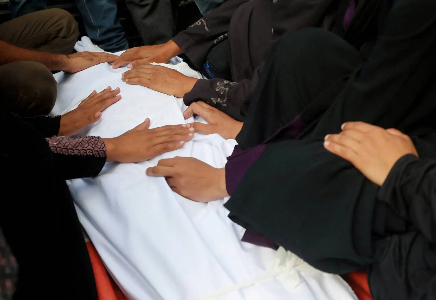 فلسطينيون قبل تشييع جثمان أحد مواطنيهم ممن قُتلوا بنيران إسرائيلية خلال تلقى المساعدات أمس في غزة (رويترز)