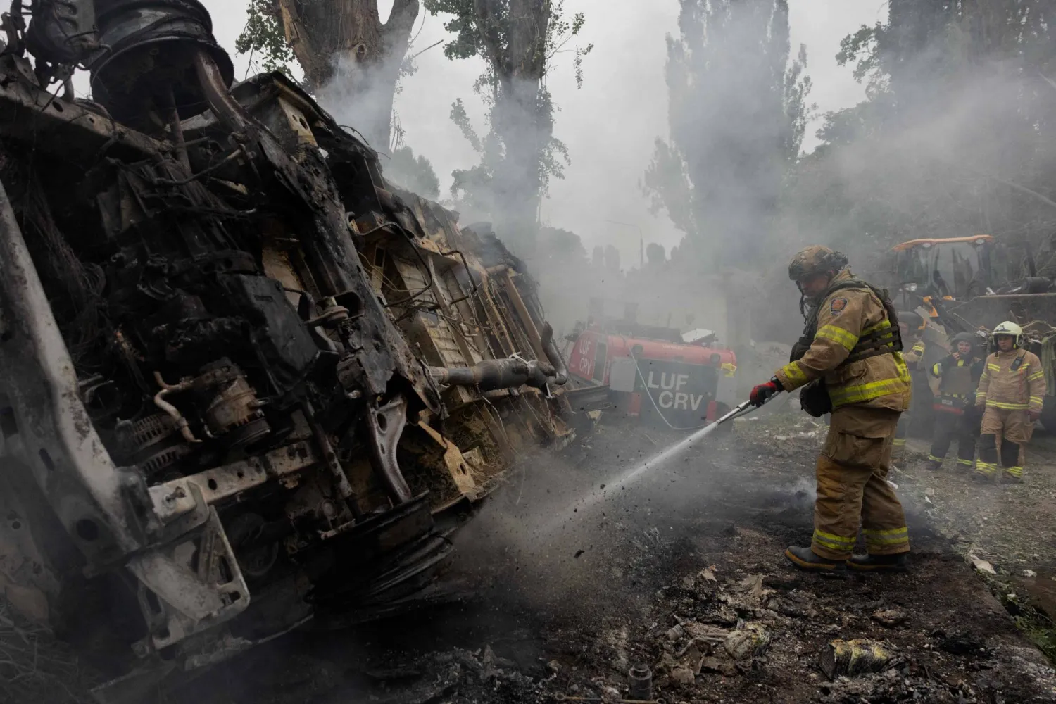 A firefighter works to extinguish a fire of a burnt-out car following a Russian attack in Kyiv on July 31, 2025, amid the Russian invasion of Ukraine. (Photo by Tetiana DZHAFAROVA / AFP)