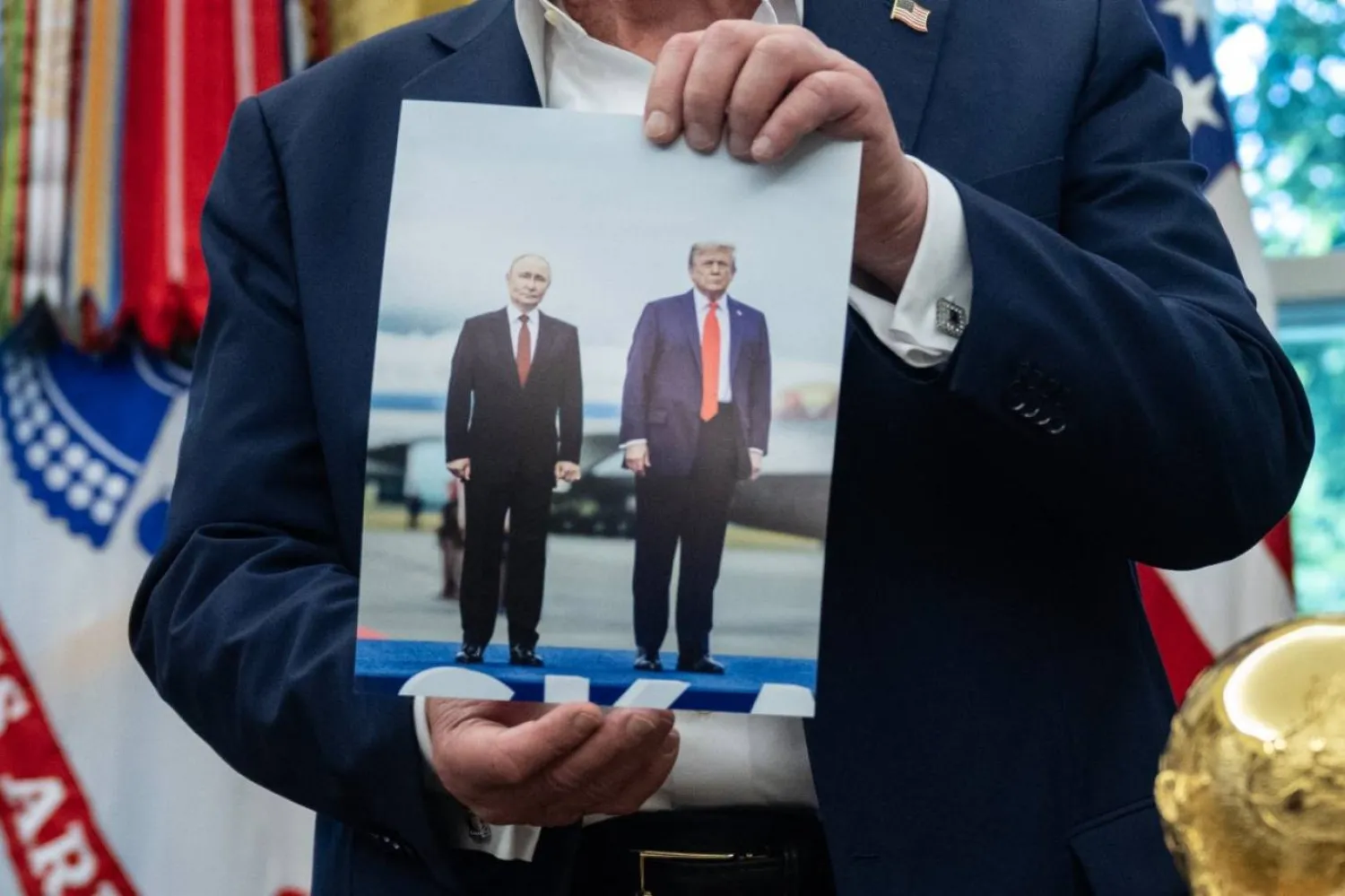 Trump, Alaska'da Putin'i karşılarken çekilmiş bir fotoğrafını gazetecilere gösterirken (AFP)
