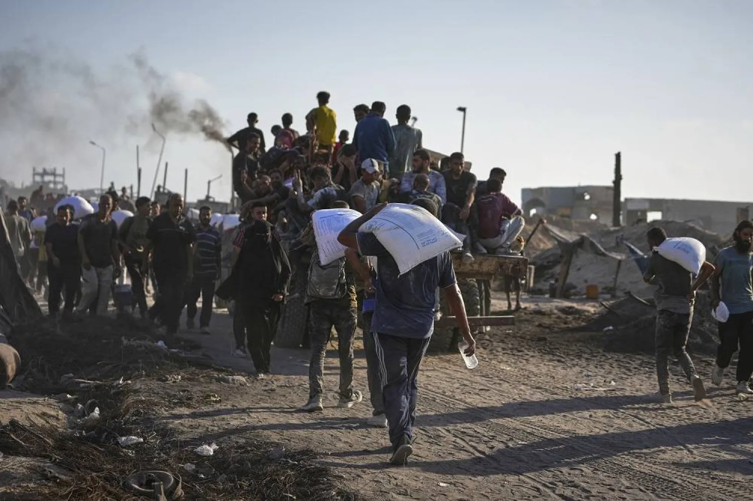 Palestinians ride on trucks from a humanitarian aid convoy bound for Gaza City from the northern Gaza Strip, as others carry sacks of flour unloaded from the vehicles, Thursday, July 31, 2025. (AP)
