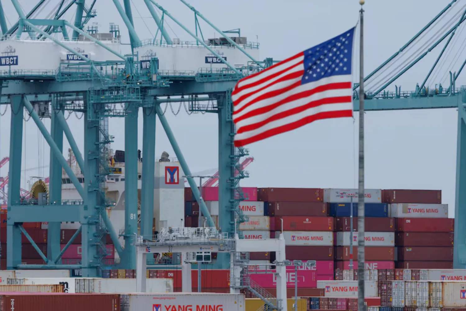 A US flag flutters near shipping containers as a ship is unloaded at the Port of Los Angeles, in San Pedro, California, US, May 1, 2025. REUTERS/Mike Blake/ File Photo 