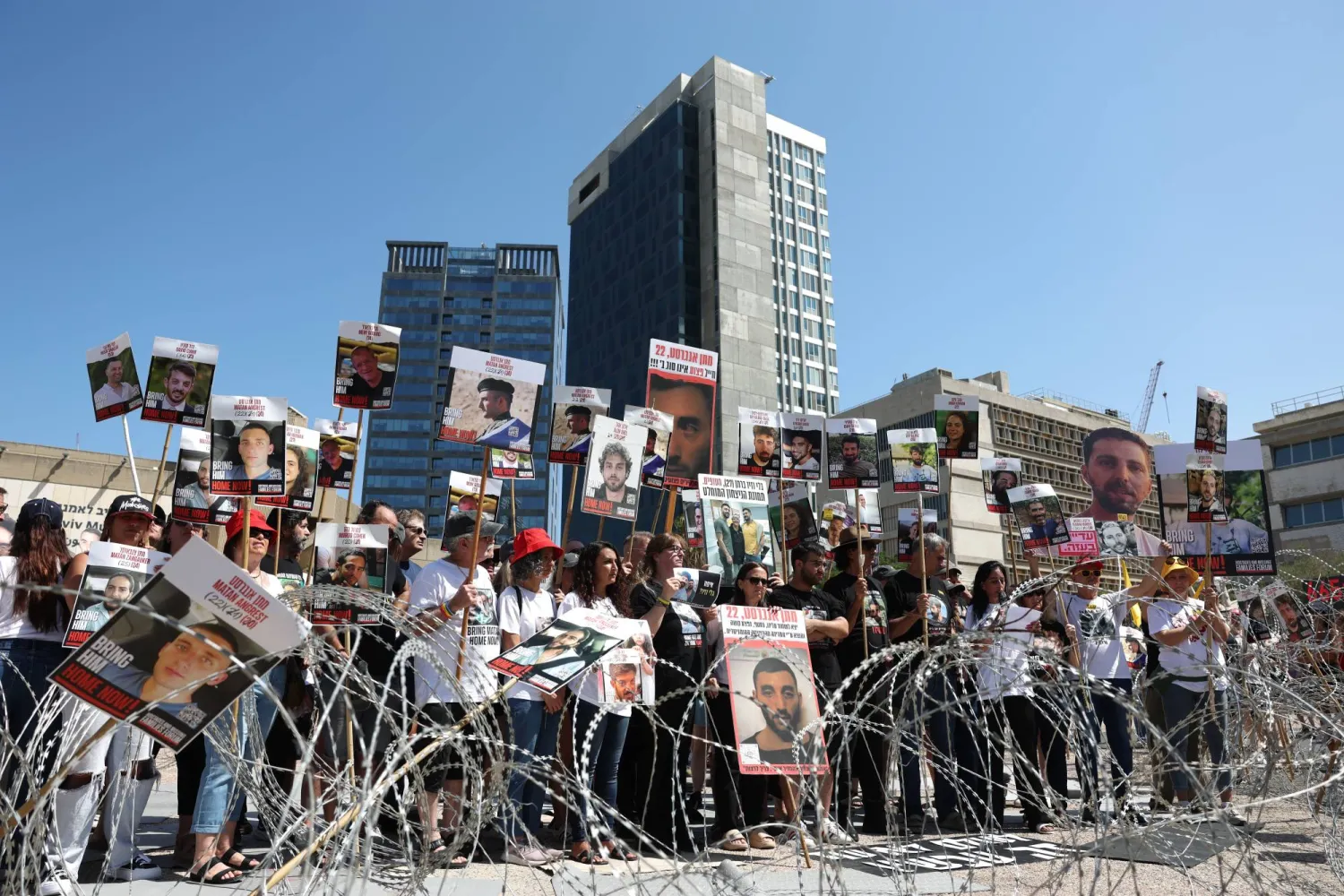 محتجون إسرائيليون يحملون صور رهائن خارج مقر للجيش في تل أبيب (إ.ب.أ)