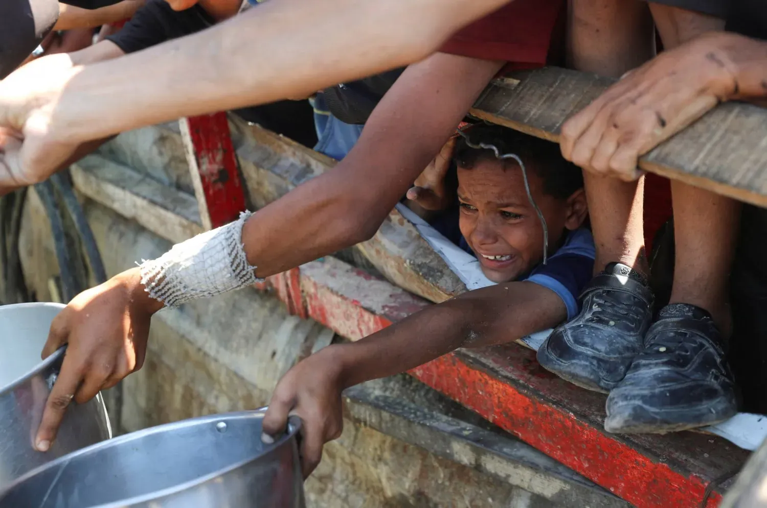 Filistinli çocuklar bugün Gazze Şehri'ndeki bir aşevinden yiyecek almakta zorlanıyor (Reuters)