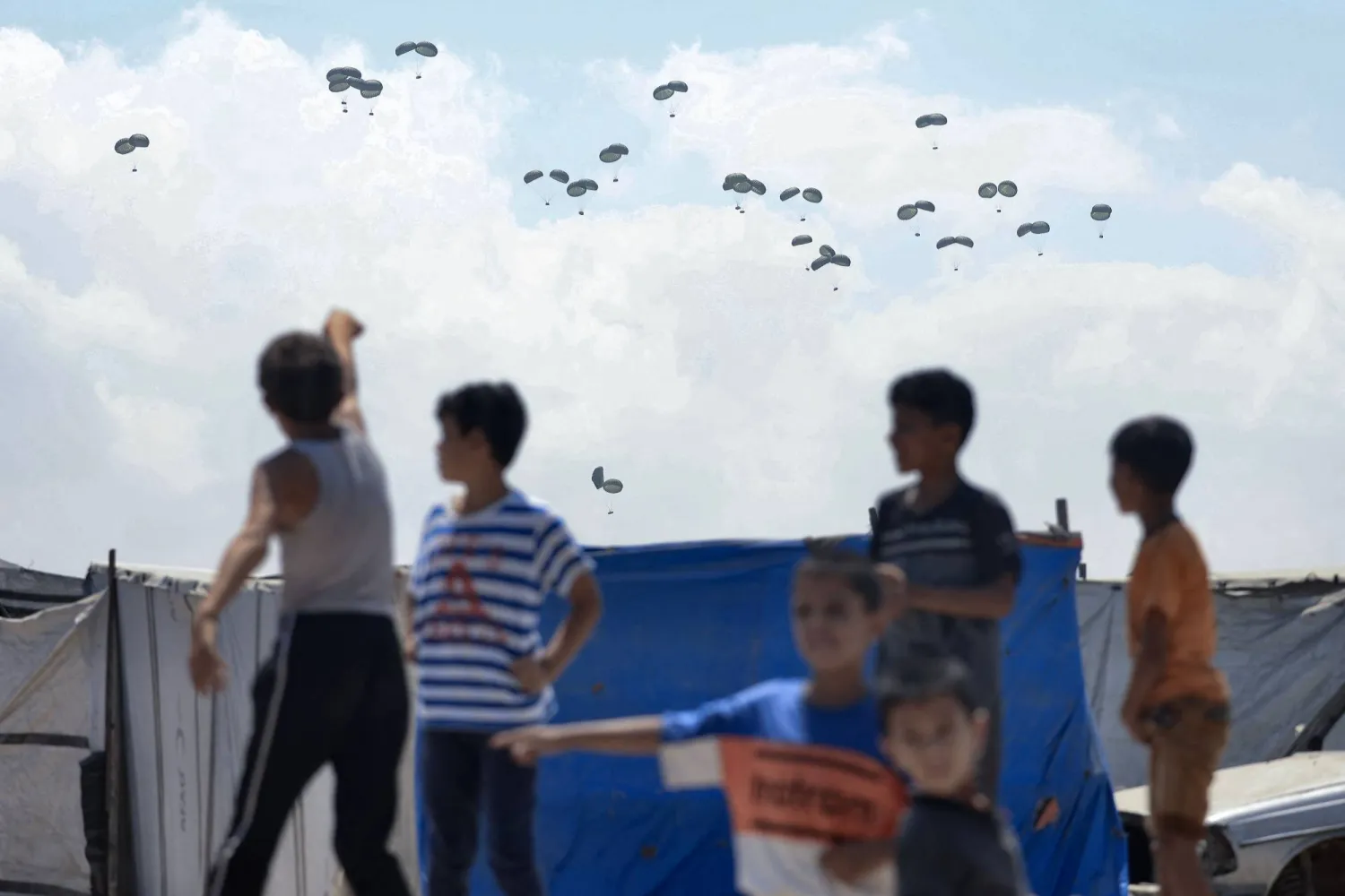 أطفال يراقبون إسقاط رزم مساعدات إنسانية فوق رفح السبت (أ.ف.ب)