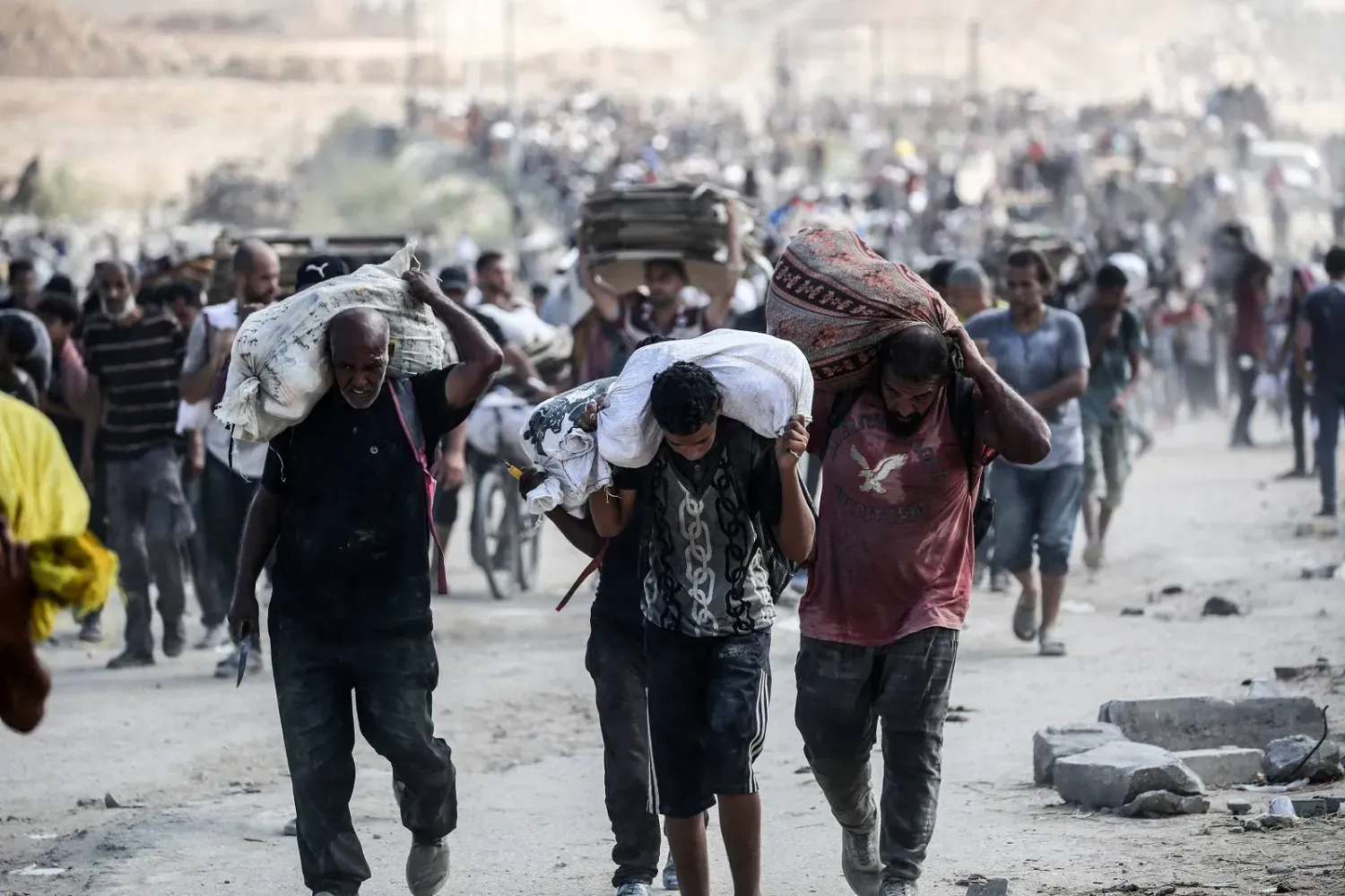 Gazze Şeridi'nin orta kesimindeki Netzarim Koridoru yakınlarında gıda yardımlarını taşıyan Filistinliler (AFP)