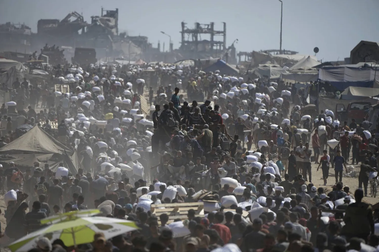 فلسطينيون يحملون أجولة من المساعدات الإنسانية في طريقهم إلى مدينة غزة (أ.ب)