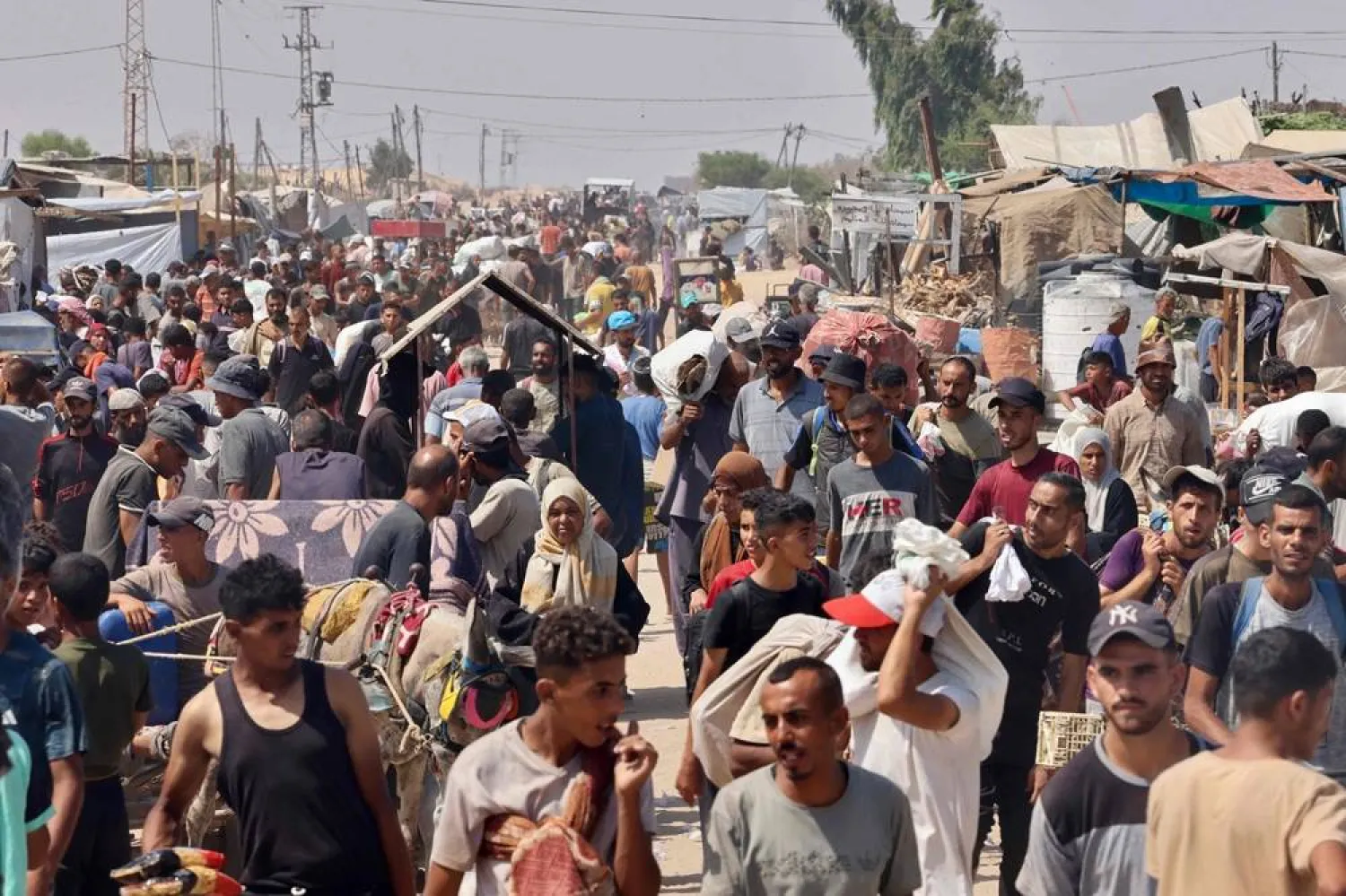 Palestinians carry humanitarian aid they received at the Rafah corridor as they walk in the Mawasi area of Rafah in the southern Gaza Strip on July 30, 2025. (AFP) 