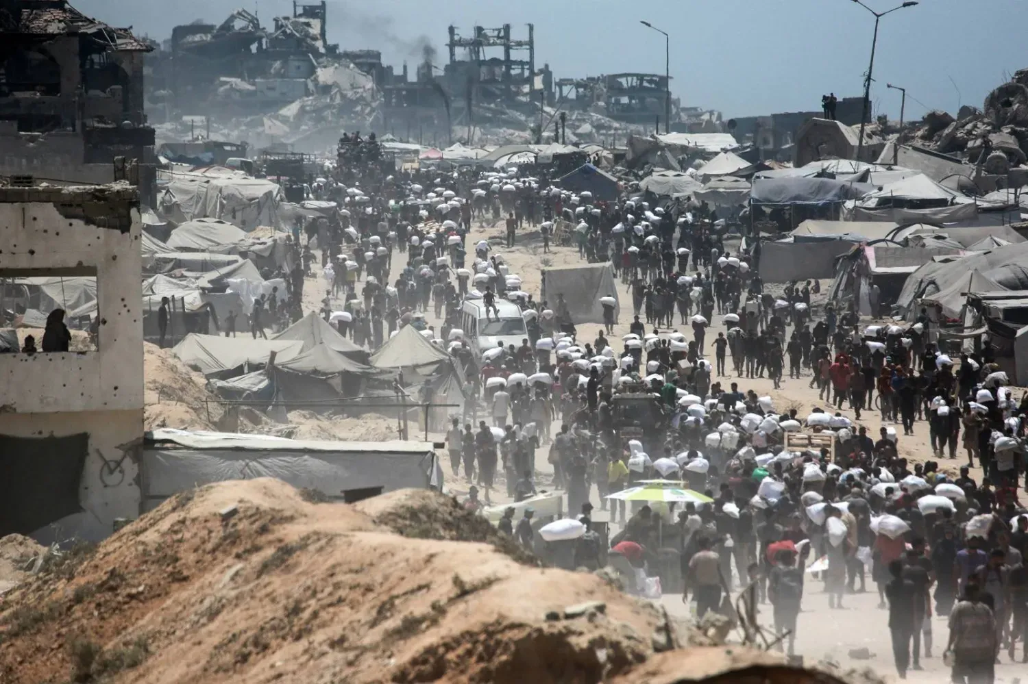Gazze Şeridi'nin kuzeyinde bulunan Cibaliye'deki Zikim Sınır Kapısı’ndan Gazze Şeridi'ne giren yardım kamyonlarından aldıkları un çuvallarını taşıyan Filistinliler (AFP)