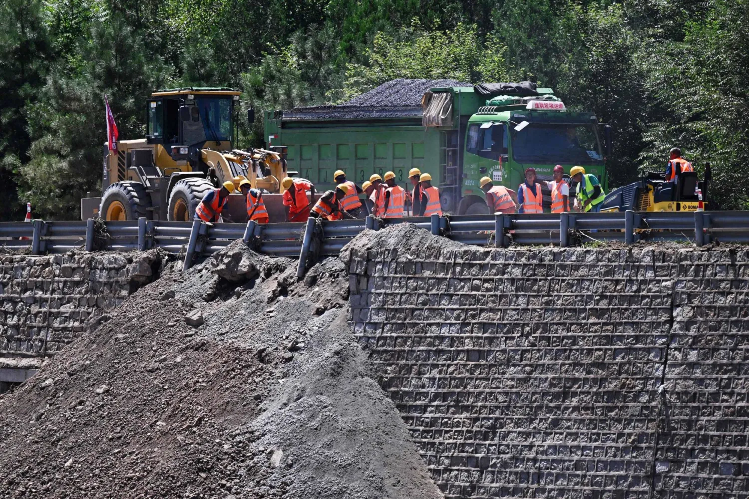 عمال يزيلون الأنقاض من منطقة تضررت بالفيضانات بعد هطول أمطار غزيرة في منطقة هوايرو على مشارف بكين في 30 يوليو الماضي (أ.ف.ب)