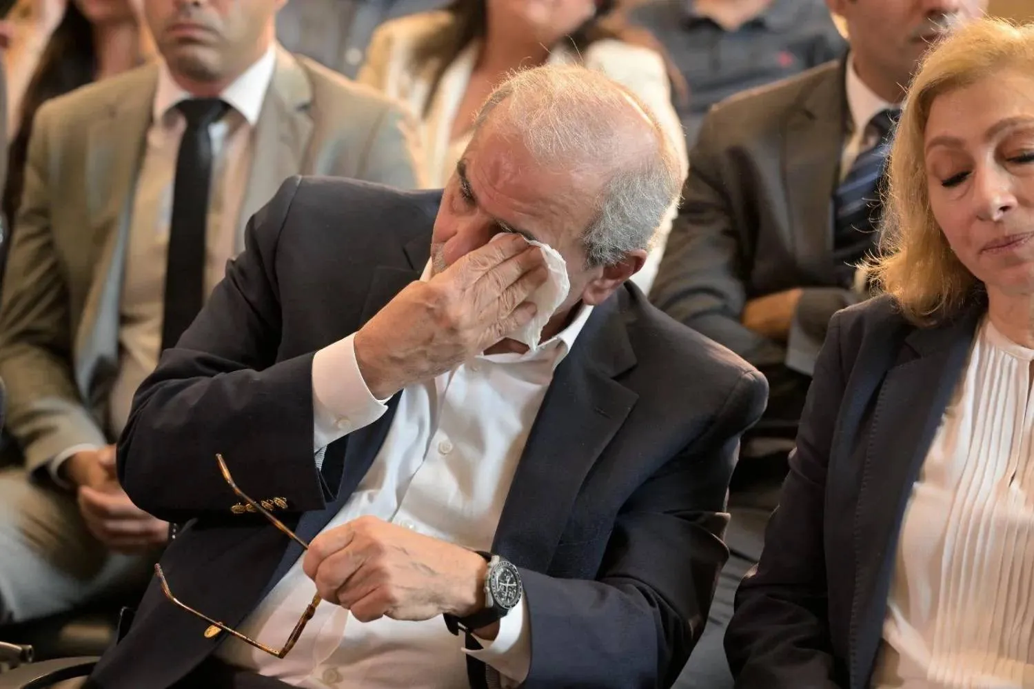 Prime Minister Nawaf Salam wipes his tears as he listens to a relative of a Beirut port explosion victim speak about her plight. (Asharq A-Awsat) 