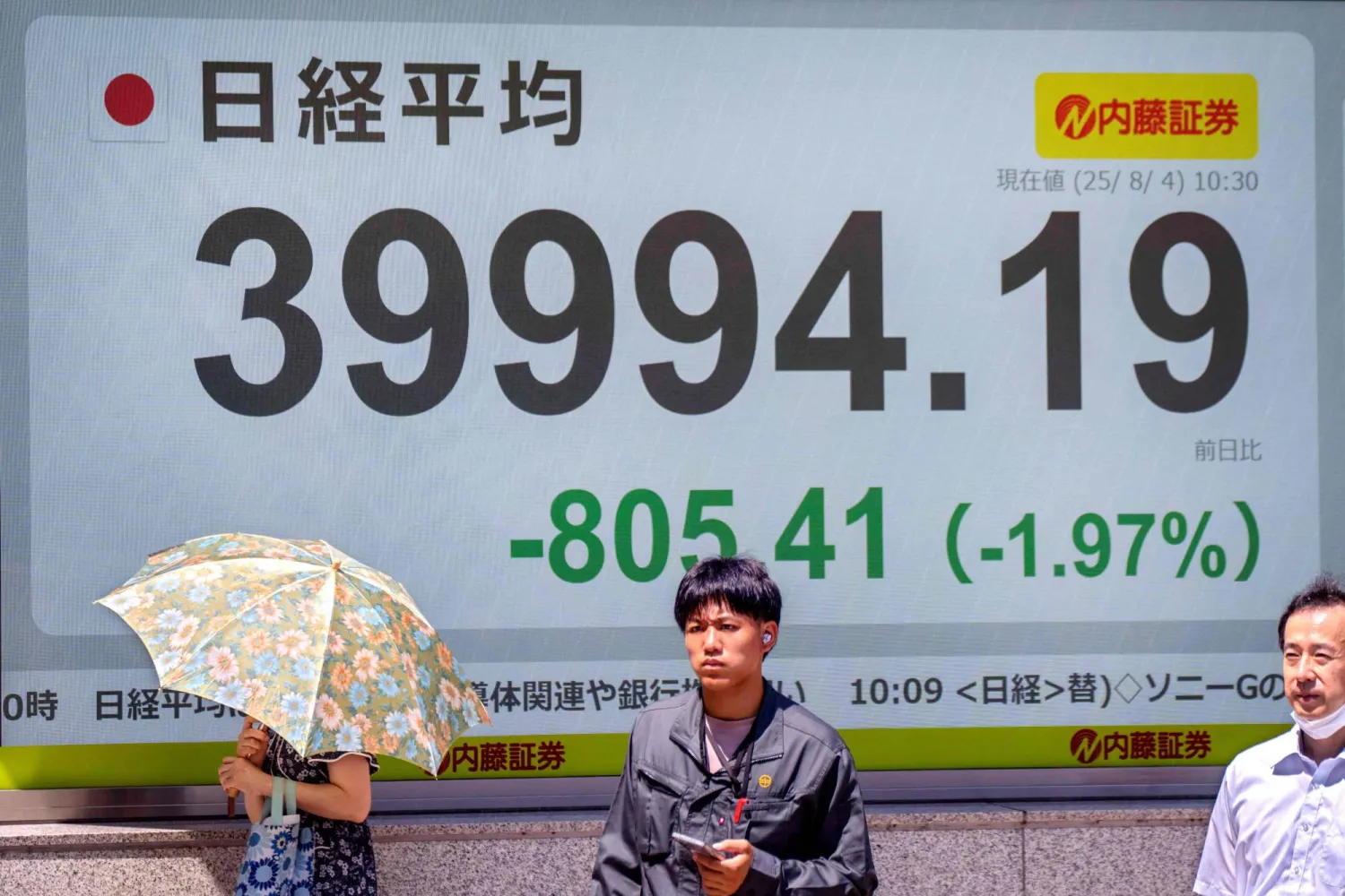 مشاة يمرون أمام لوحة تعرض حركة الأسهم بوسط العاصمة اليابانية طوكيو (أ.ف.ب)