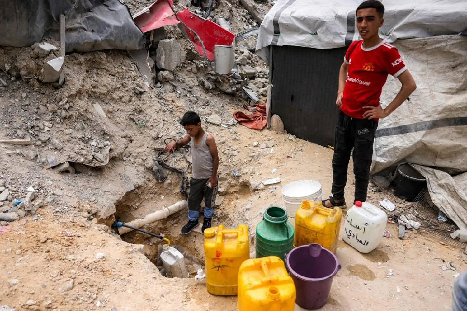 A boy fills up containers with water from the remaining water still left in underground pipes, in Beit Lahia in the northern Gaza Strip on April 24, 2025. (AFP)