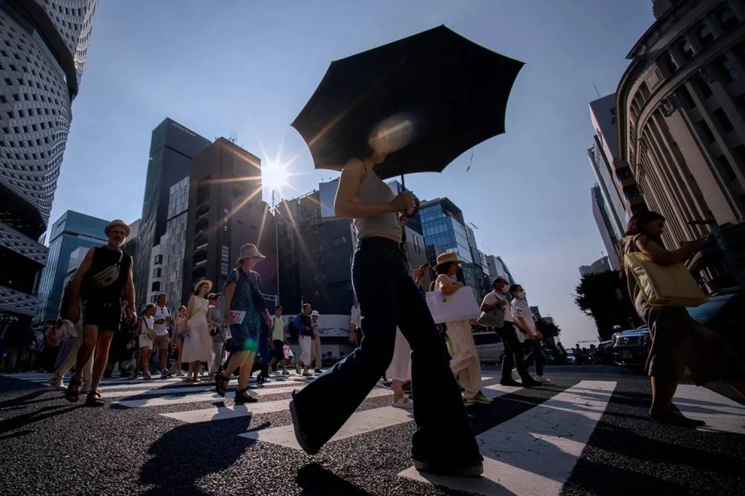 People cross a street on a hot day in Tokyo on August 4, 2025. (AFP) 
