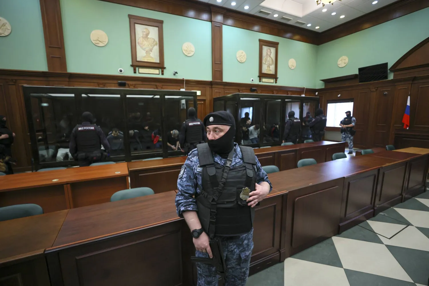 يحضر المتهمون (في الخلف) في قضية الهجوم الإرهابي على قاعة كروكس سيتي هول جلسة استماع في المحكمة العسكرية للمنطقة الغربية الثانية في موسكو بروسيا في 4 أغسطس/آب 2025. أُلقي القبض على 19 شخصاً في موسكو على خلفية الهجوم الإرهابي على قاعة كروكس سيتي هول للحفلات الموسيقية في كراسنوجورسك بمنطقة موسكو (إ.ب.أ)